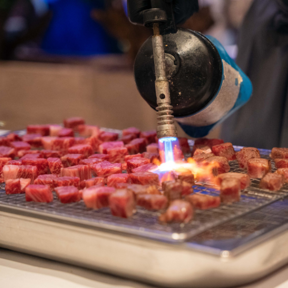 Fleisch wird mit einem Bunsenbrenner angegrillt
