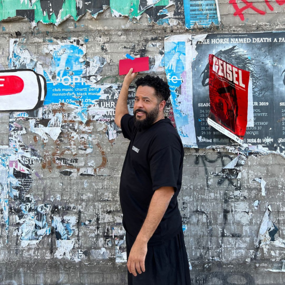 Adel Tawil hält eine rote Karte an einer Wand