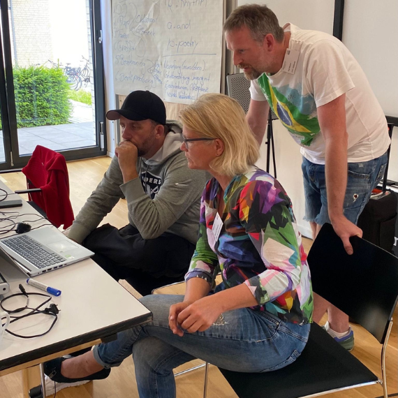Dr. Susanne Schaefer und zwei Herren arbeiten konzentriert zusammen am Laptop